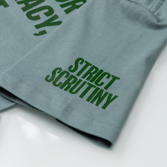 Green text on a folded piece of fabric with 'Strict Scrutiny' visible