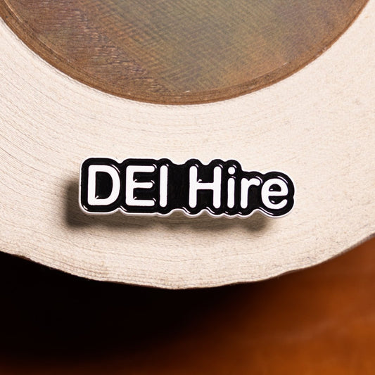 Pin with 'DEI Hire' text on a beige cap