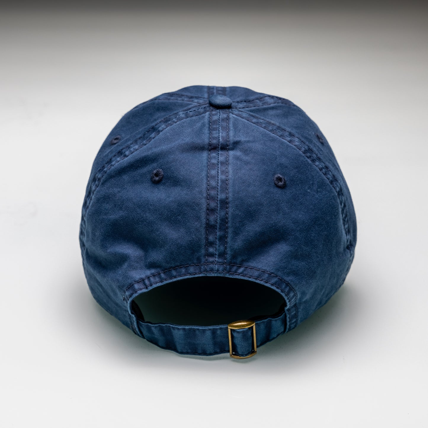 Blue denim cap with a gold buckle on a light gray background