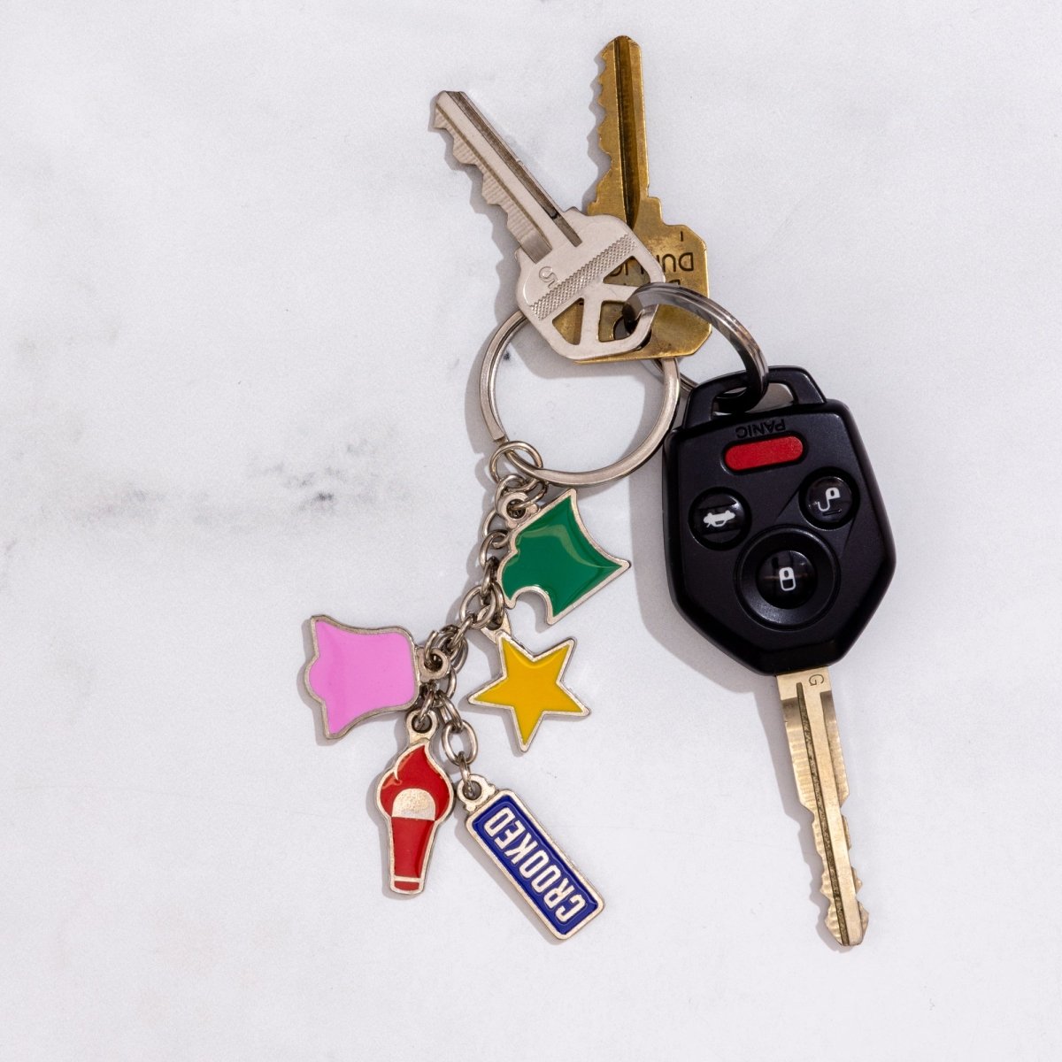 Keychain with various charms attached to keys on a light gray background