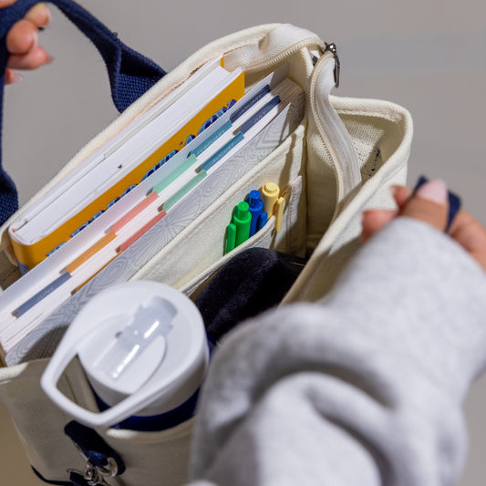 Open beige pouch with stationery items including books, pens, and a water bottle.