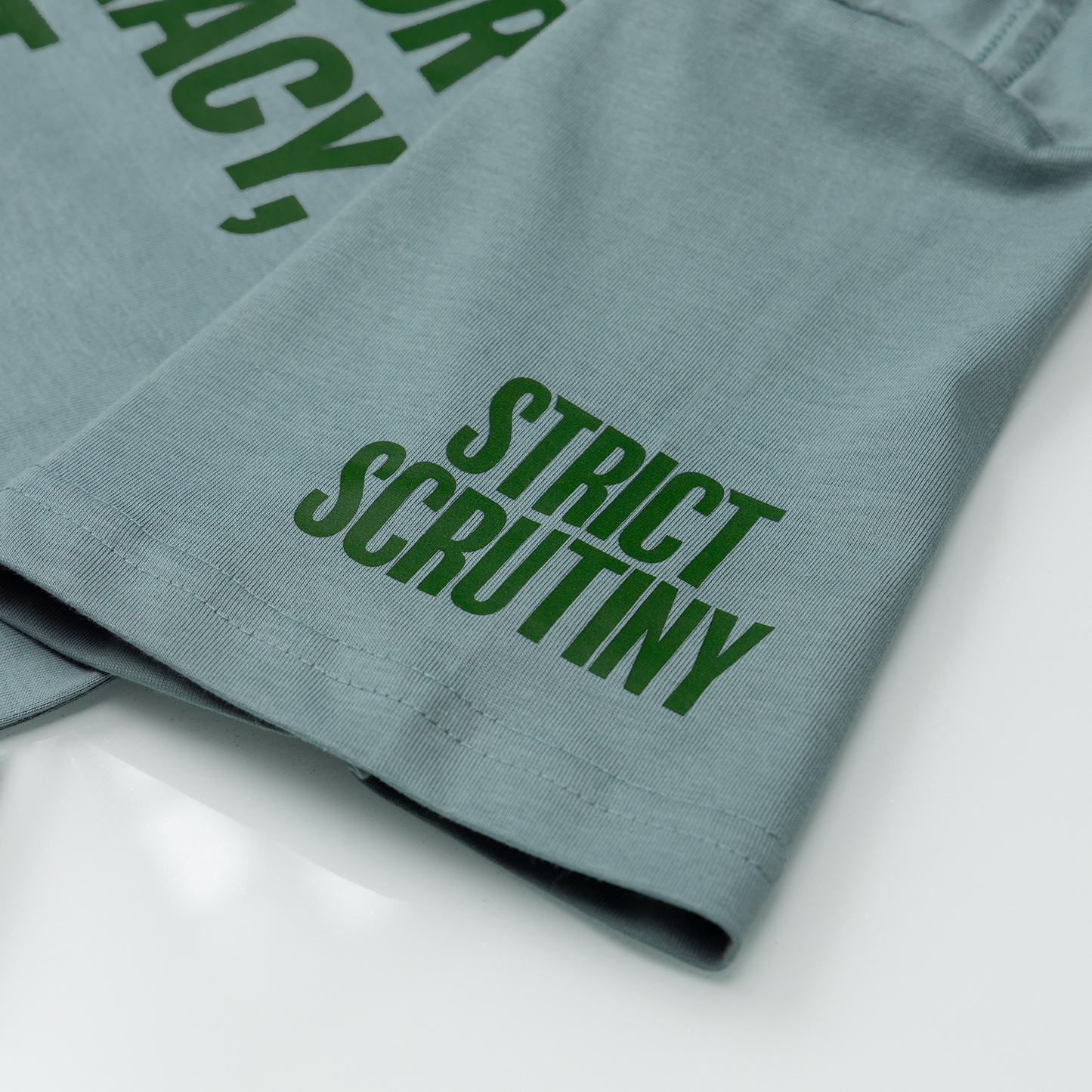 Green text on a folded piece of fabric with 'Strict Scrutiny' visible