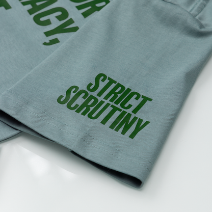 Green text on a folded piece of fabric with 'Strict Scrutiny' visible