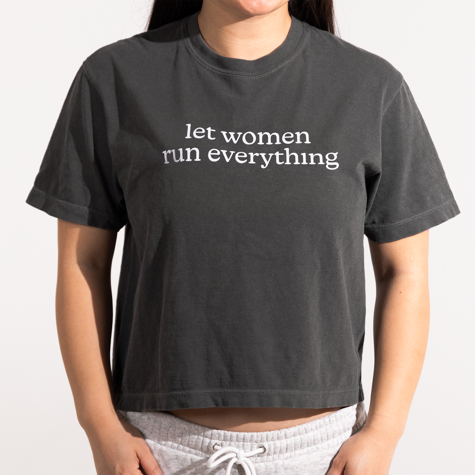 Model wearing grey boxy tshirt that says "let women run everything"